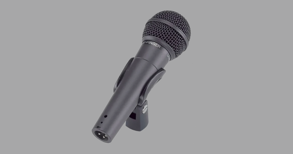 Criador de conteúdo aplicando a técnica de proximidade correta no Behringer XM8500 para obter uma voz com graves presentes e som de rádio, ideal para streaming e locução.