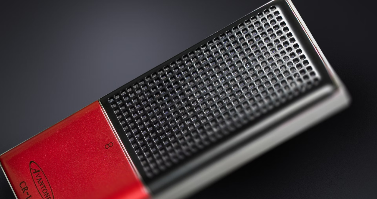 O microfone de fita Avantone CR-14 em destaque no seu shock mount, com foco no seu design vintage e na grade prateada, em um ambiente de estúdio profissional.