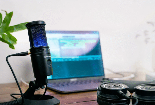 Microfone condensador Audio-Technica AT2020 em um pedestal, com fundo escuro, destacando seu design para uso em home studio.