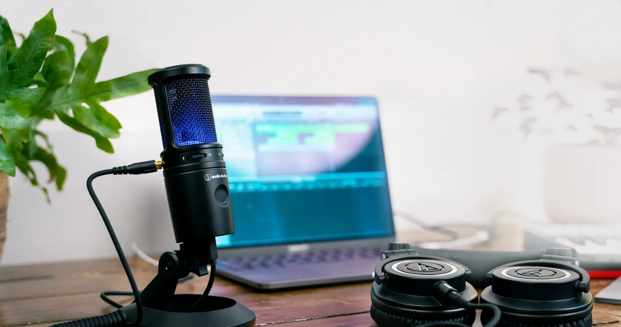 Microfone condensador Audio-Technica AT2020 em um pedestal, com fundo escuro, destacando seu design para uso em home studio.