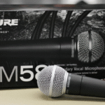 O microfone dinâmico Shure SM58, o padrão da indústria para vocais, em destaque com sua icônica grelha esférica prateada.