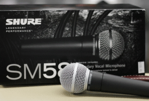 O microfone dinâmico Shure SM58, o padrão da indústria para vocais, em destaque com sua icônica grelha esférica prateada.