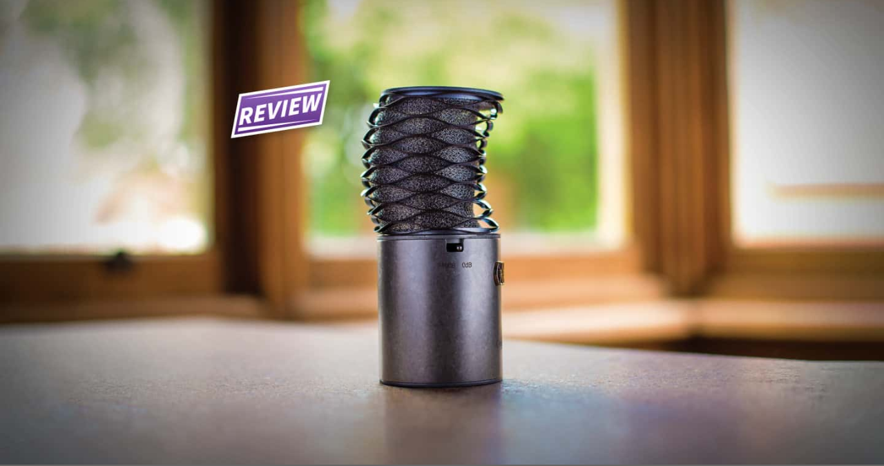 O microfone condensador Aston Origin em um pedestal de estúdio, com seu chassi de aço rústico em destaque para review completo.