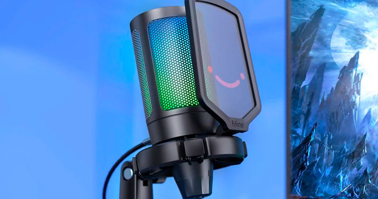 Microfone Fifine A6V com iluminação RGB ativa em um setup gamer moderno, destacando seu design compacto, filtro pop e suporte shock mount para streaming e podcasts.
