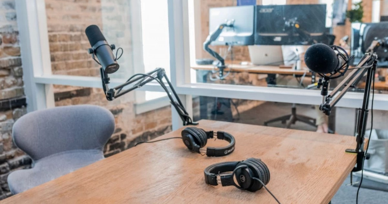 Uma bancada de estúdio de gravação profissional exibindo os quatro melhores microfones para podcast analisados no artigo: Shure SM7B, Rode ProCaster, Rode NT-USB e Blue Yeti, prontos para transmissão.