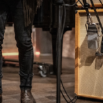 Microfone de fita Warm Audio WA-44 com design vintage clássico inspirado no RCA 44, posicionado em um pedestal de estúdio profissional com acabamento metálico premium.