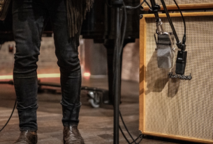 Microfone de fita Warm Audio WA-44 com design vintage clássico inspirado no RCA 44, posicionado em um pedestal de estúdio profissional com acabamento metálico premium.